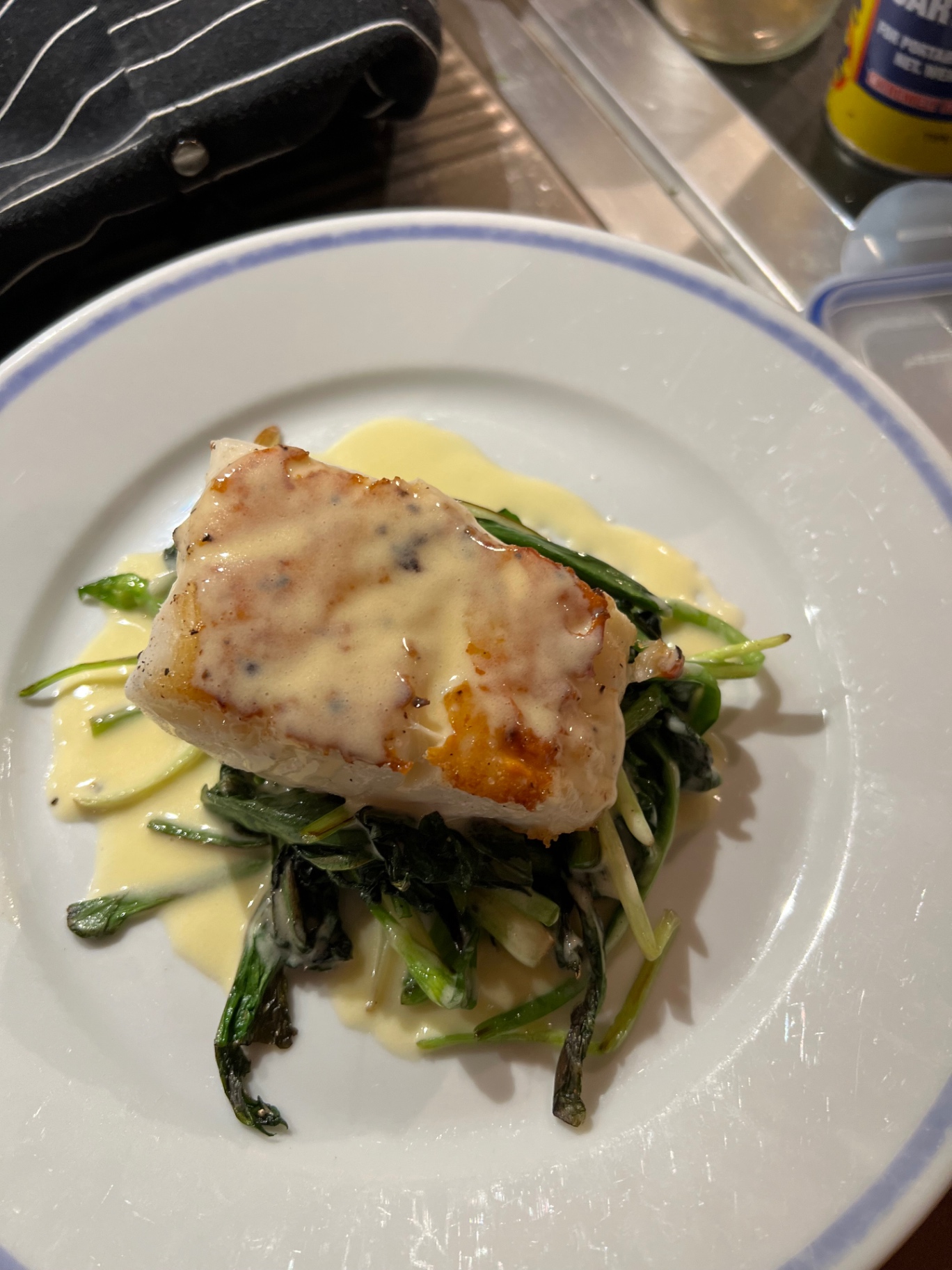 Pan-seared cod loin on wilted samphire and sea greens with a classic beurre blanc — fine dining fish course plated at a Lovey Chef private dinner in Bristol