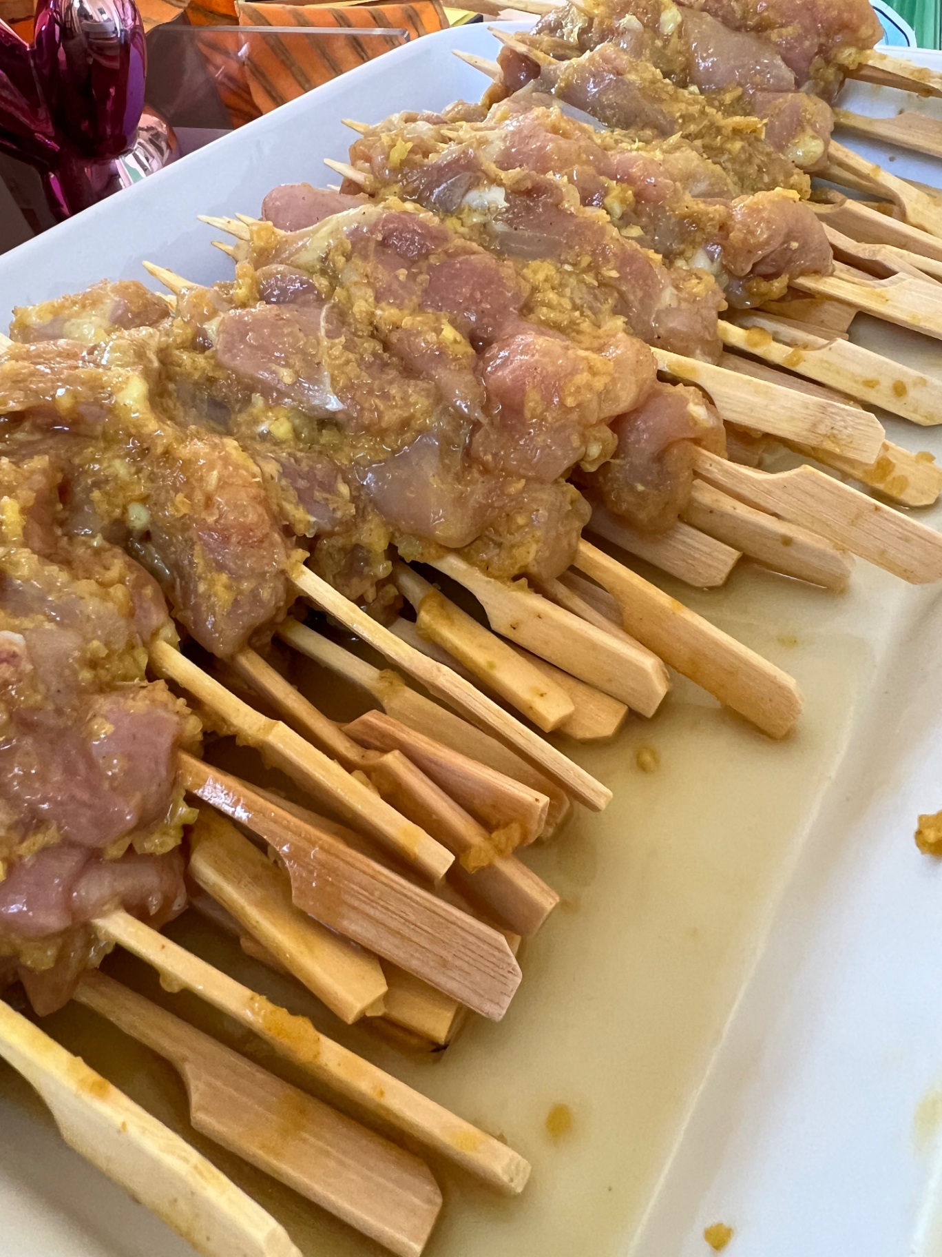 Free-range chicken thigh satay skewers in a turmeric, ginger and lemongrass marinade on bamboo sticks, ready for the charcoal grill at a Lovey Chef private BBQ