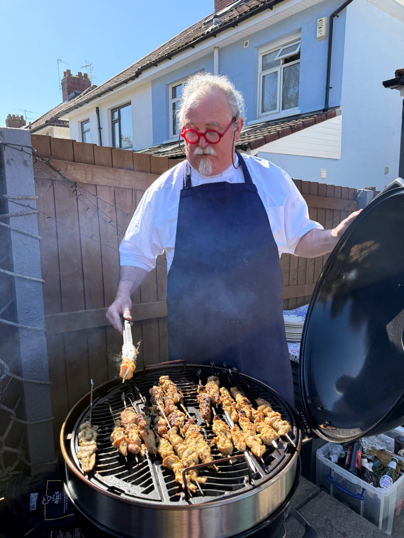 Personal chef Gus Longstaff grilling chicken satay skewers over charcoal on a Weber kettle BBQ in a Bristol garden — Lovey Chef private BBQ catering